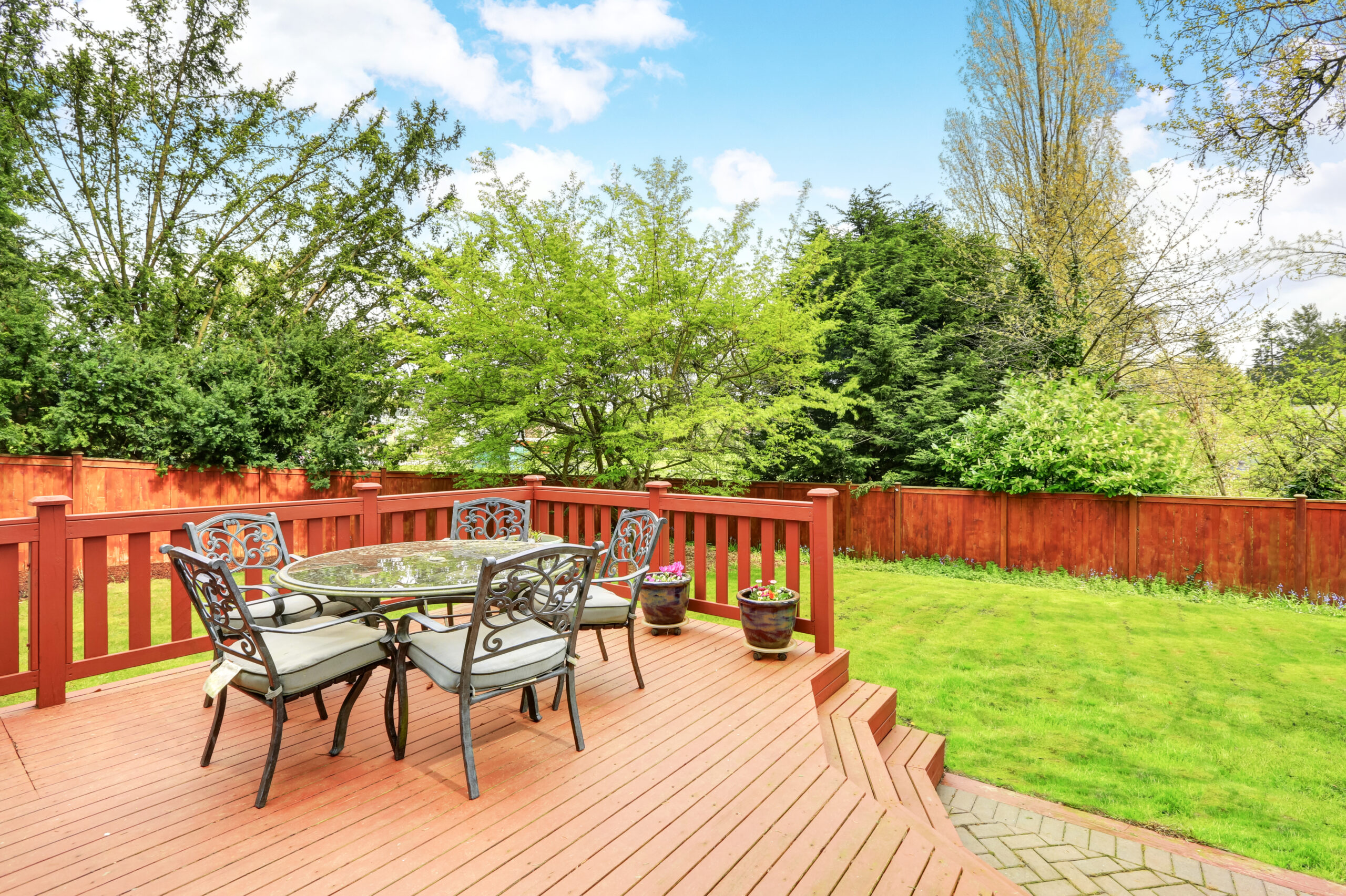 Large deck with dining space overlooking spacious back yard.